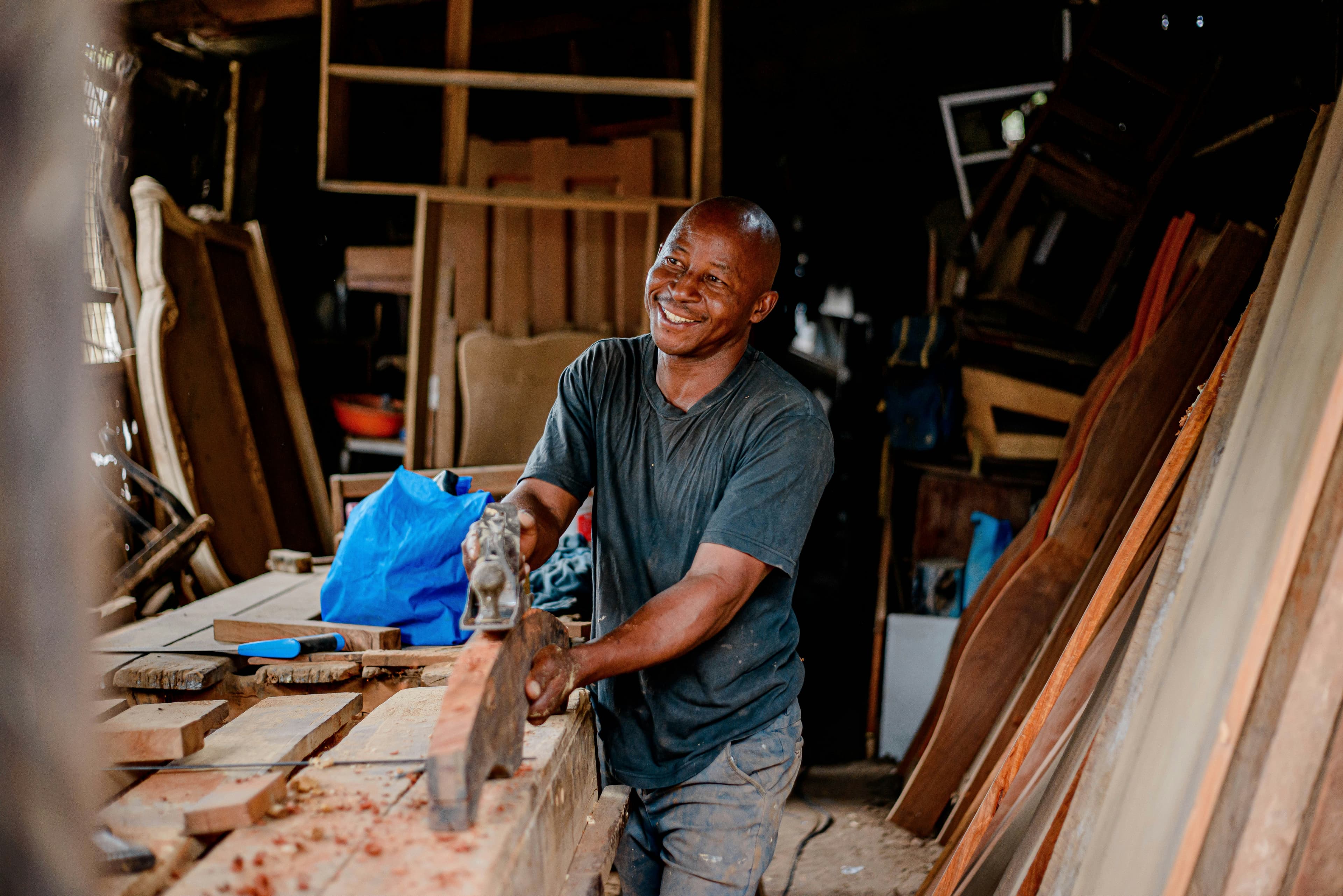 Carpenter smiling while working with wood in his workshop